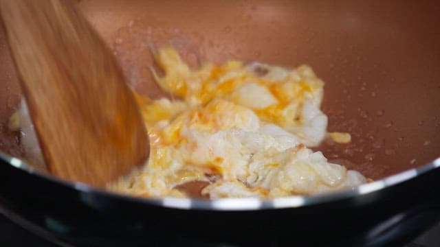 Cooking scrambled eggs with a spatula in a frying pan