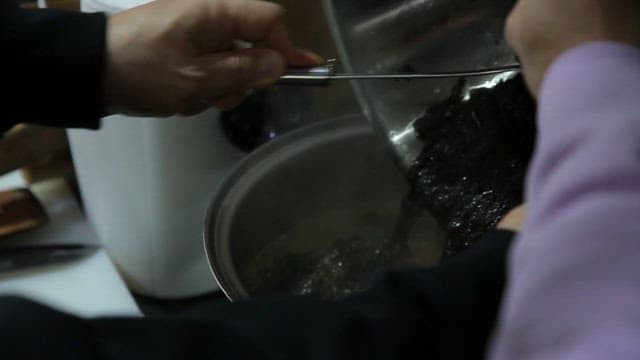 Adding the laver to the broth boiling in a pot