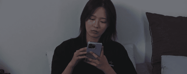 침대에 앉아 휴대폰을 사용하는 여성