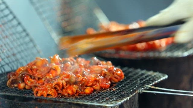 Sizzling small octopuses on a grill