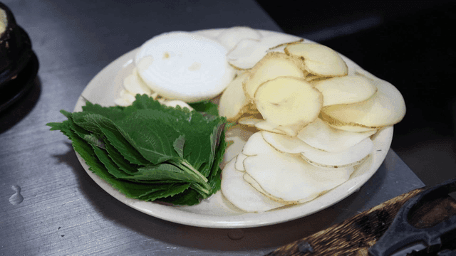 Plate containing thinly sliced ​​potatoes and perilla leaves