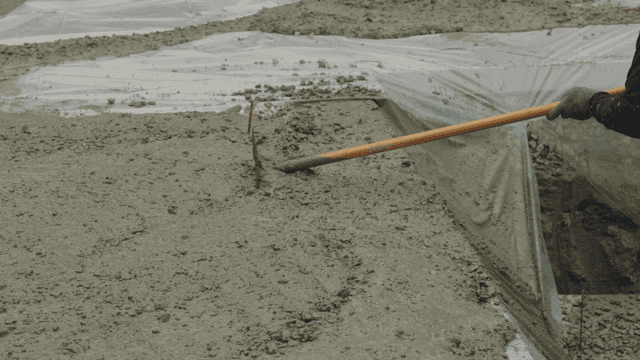 Worker leveling wet concrete with a rake