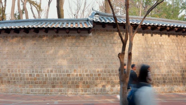 Traditional Korean wall with people passing by