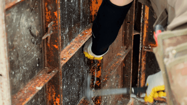 녹슨 금속 프레임에 도구 사용하는 작업자