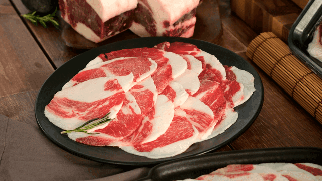 Thinly sliced raw beef on a black plate