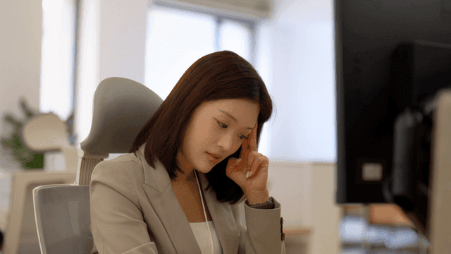 Office worker pressing down on her head in office
