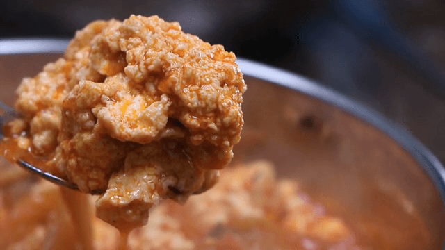 Spoonful of spicy seafood soup with soft bean curd