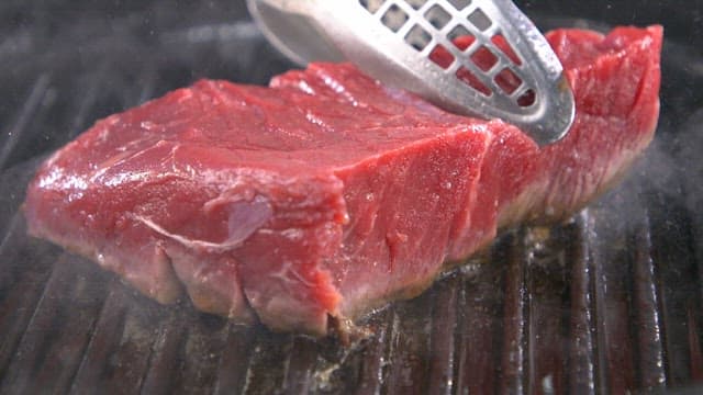 Grilling a juicy beef steak on a hot pan