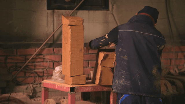 실내에서 점토 블록을 다듬는 작업자