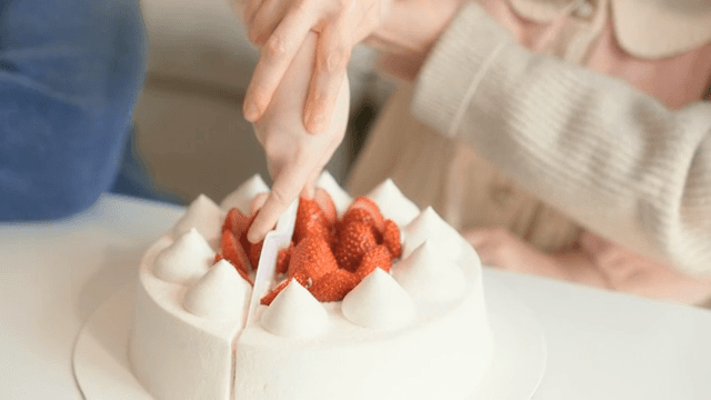 Mother and daughter cutting a strawberry cake