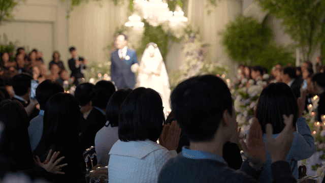 Bride and her father enter wedding hall where guests applaud.