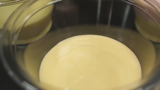 Pouring pink batter into a bowl of yellow batter