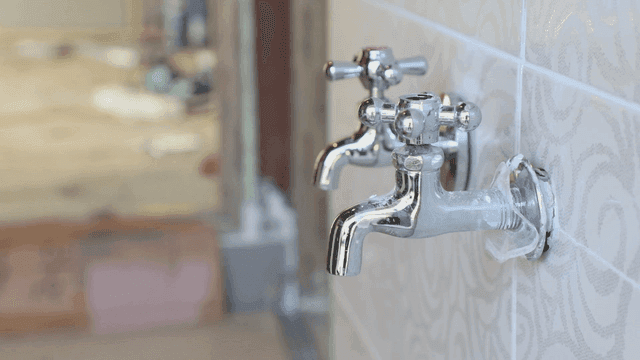 타일 벽에 설치된 금속 수도꼭지