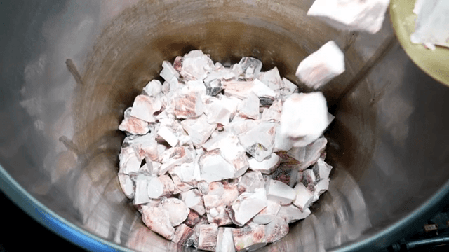 큰 금속 용기에 담긴 냉동 고기 조각