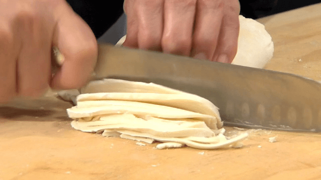 나무 도마 위에서 반죽을 자르는 손