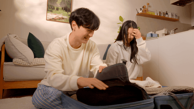 Couple packing clothes into travel suitcase