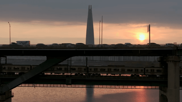 Sunset over a bridge with trains and cars
