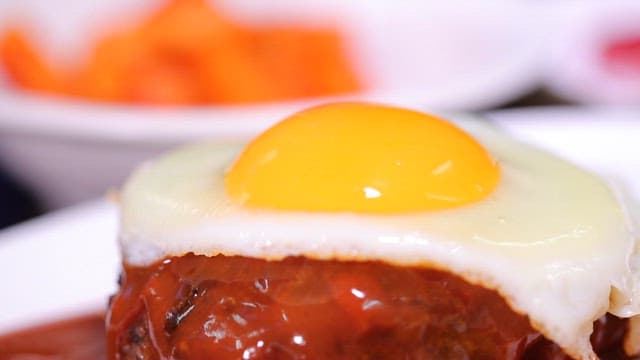 Cutting a hamburger steak with a fried egg and sauce