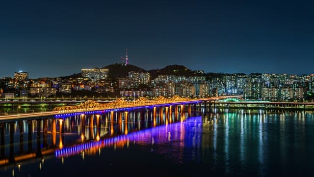 Illuminated Riverside Cityscape and Bridge at Night