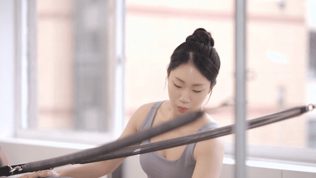 Pilates instructor assists a student indoors