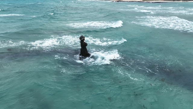 Statue in the ocean with waves