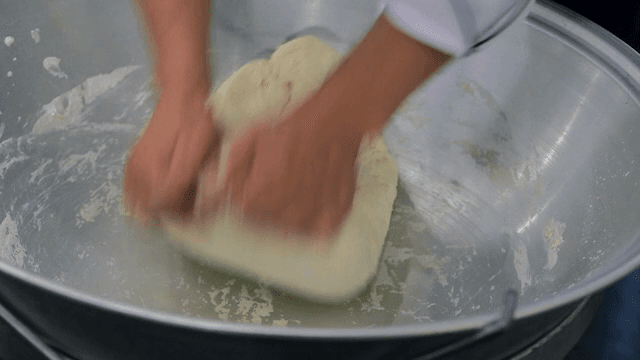 큰 그릇에서 반죽을 치대는 손