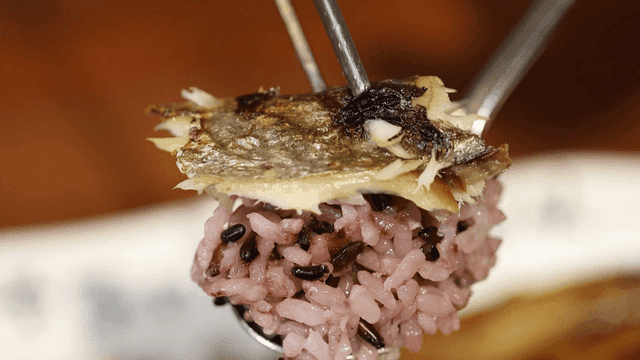 Spoonful of mixed grain rice topped with grilled mackerel.