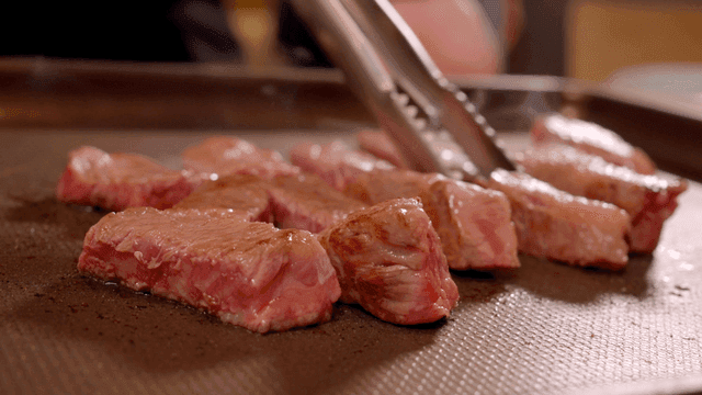 Juicy steak pieces sizzling on a grill