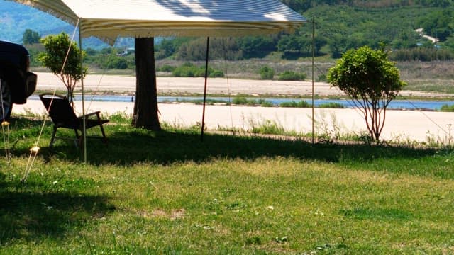 Field tent with chairs near a river on a sunny day