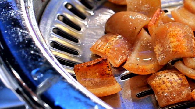 Grilling pork rinds on a metal grill