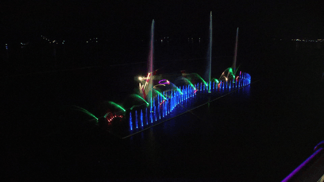 Fountain show illuminated by dazzling lights at night