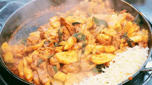 Dak-galbi cooking in a pan with cheese
