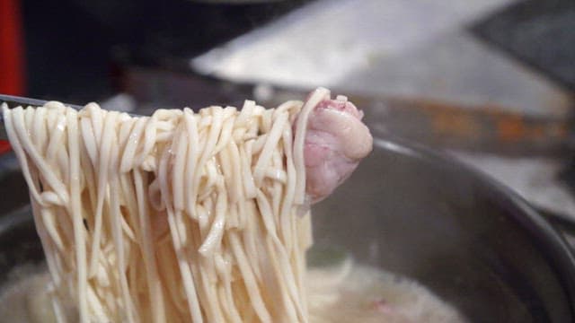 Noodles being lifted from a boiling pot