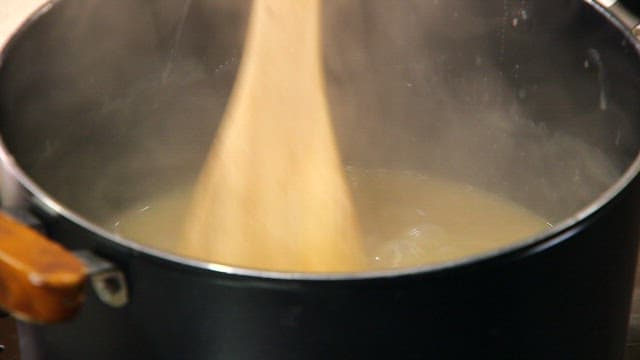 Stirring chestnut jam in a steaming pot with wooden spatula