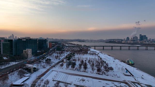 Snow-covered city at dusk with river view