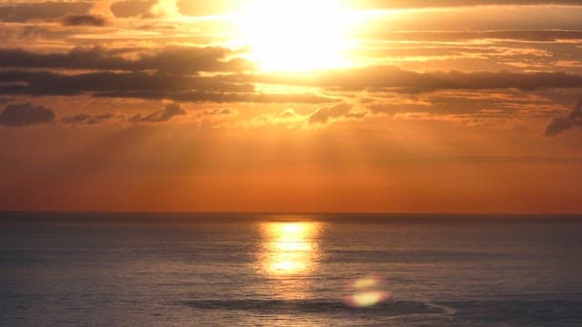 Sunset over the calm ocean with clouds