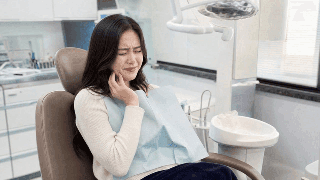 Young female patient suffering from toothache at dental clinic