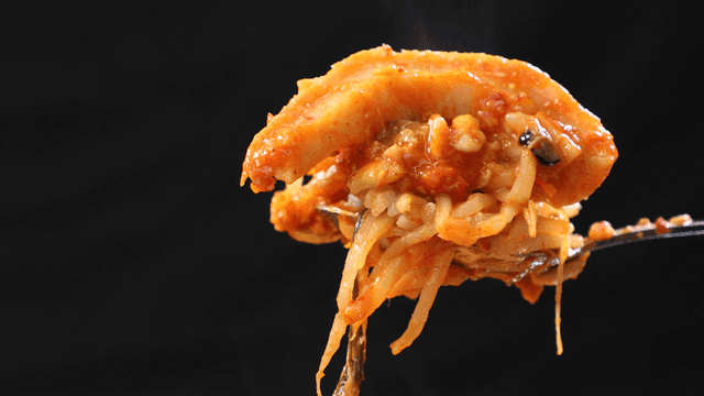 Spoon scooping up spicy braised anglerfish and rice mixed together
