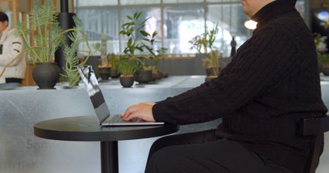 Man Working on Laptop in Plant-Filled Workspace