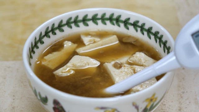 실내에서 측정기로 된장국의 염도를 테스트하는 손