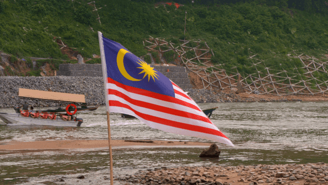 Malaysian flag waving by a riverside