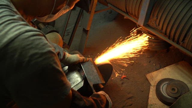 Worker sharpening a knife with sparks