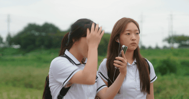 Two students walking by the riverside trail sharing earphones