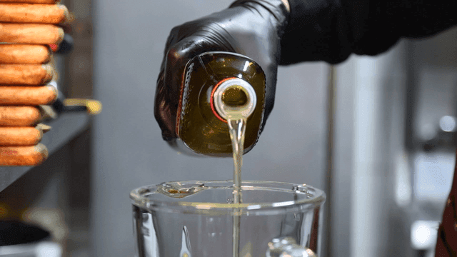 Pouring oil into a blender with avocados