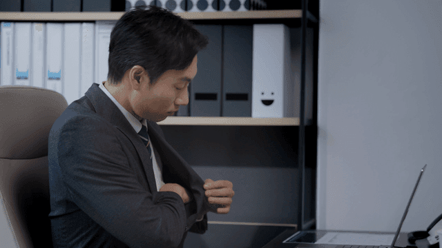 사무실 책상에 앉아 노트북을 켜는 남성