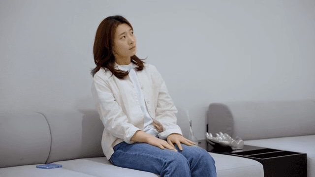 소파에 앉아 초조하게 무언가를 기다리는 여성