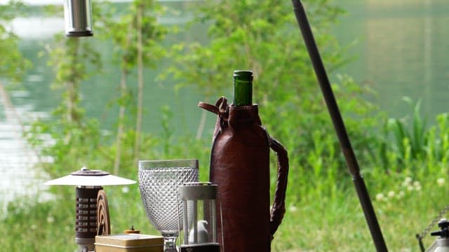 호수 옆 야외 테이블에서 유리잔에 와인을 따르는 모습