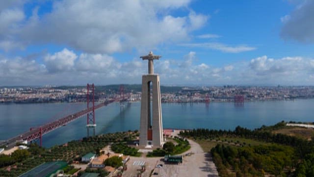 View of a large statue and suspension bridge over the river on a clear day