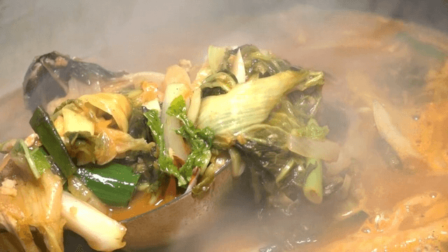 Steaming pot of spicy seafood noodle soup with vegetables