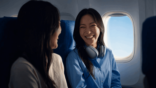 Two women smiling at each other on airplane